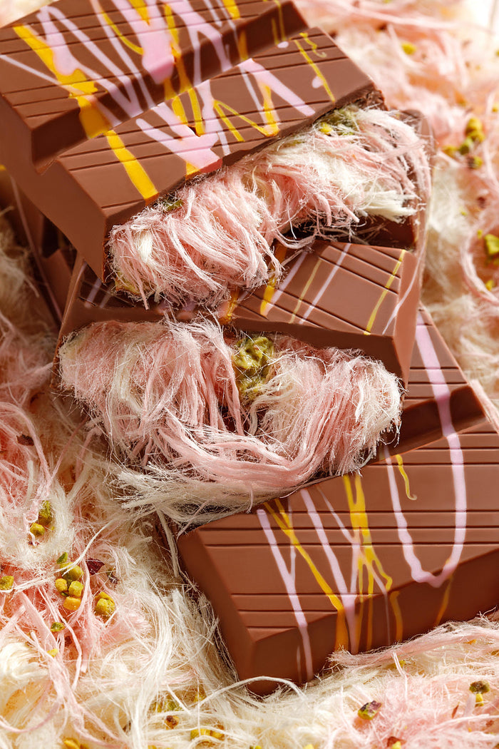 Chocolate bar with pink and white decorative strands on a textured background
