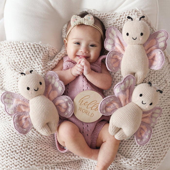 Baby smiles while laying next to Cuddle and Kind Baby Butterfly - Lavender