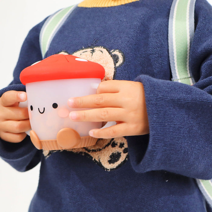 Toddler holds Itzy Ritzy Itzy Snack Cup - Ash the Mushroom