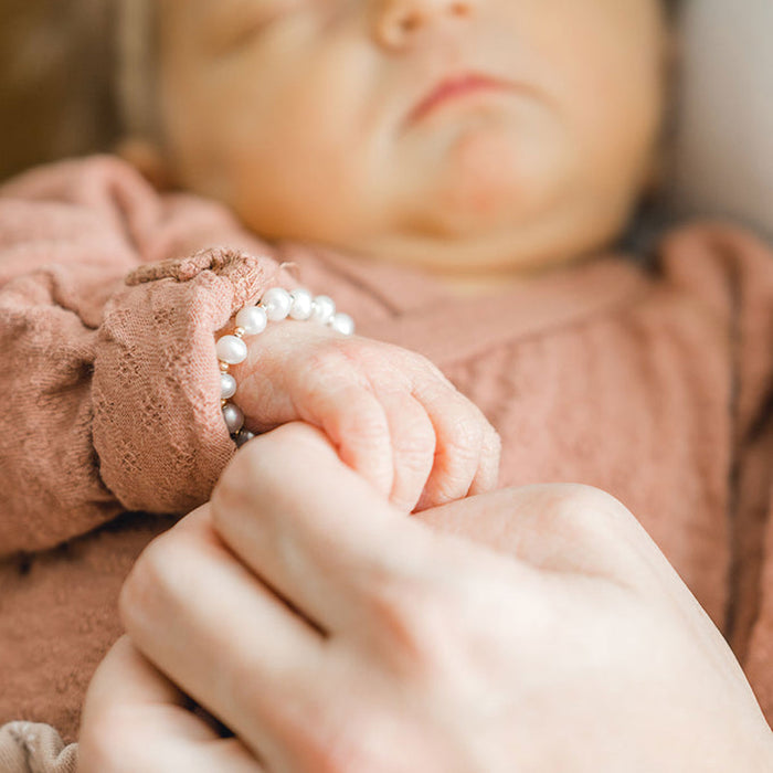 Newborn baby wearing Joyful Bead Company Fancy Pearl Bracelet