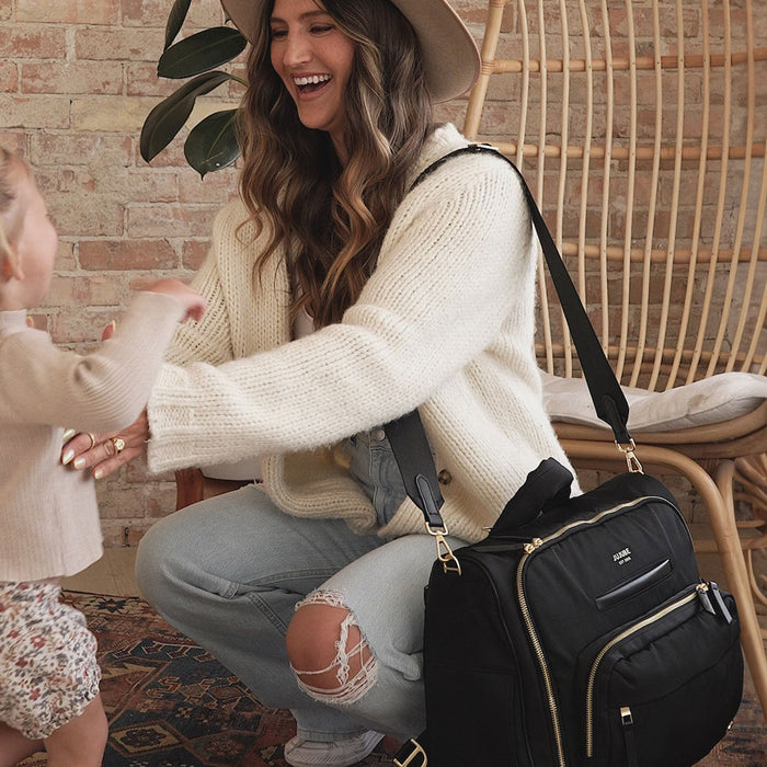 Mom smiles at baby with JuJuBe Satchel - Black on her shoulder