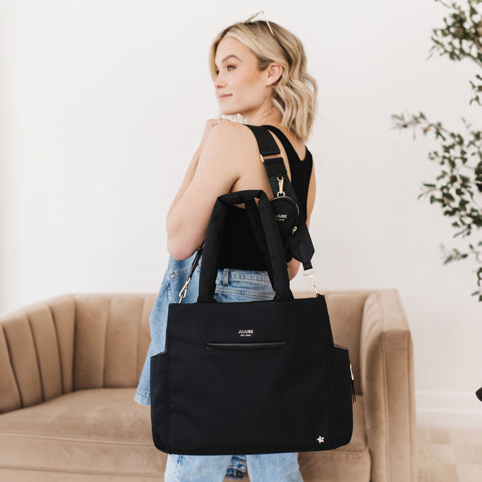Woman holding JuJuBe Utility-Strap Tote - Black over her shoulder
