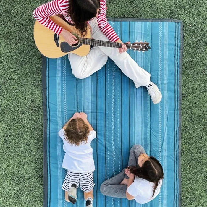 Family sits on Little Unicorn Outdoor Blanket - 5x10
