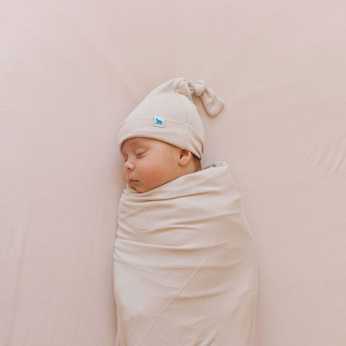 Baby sleeps while wearing Little Unicorn Stretch Knit Swaddle and Hat Set - Soft Blush
