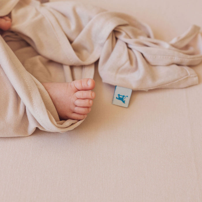 Baby's feet poke out of Little Unicorn Stretch Knit Swaddle and Hat Set - Soft Blush