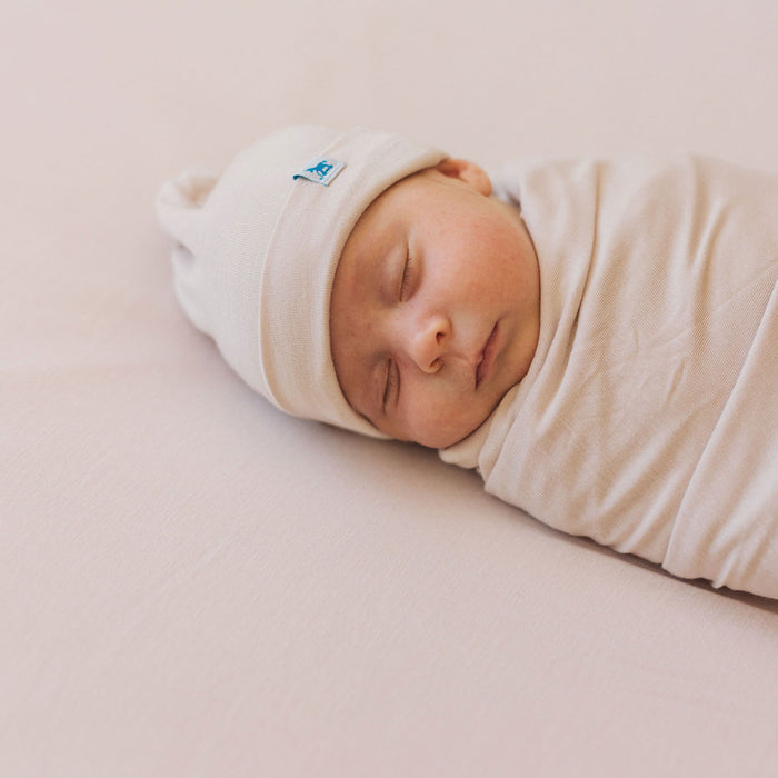 Baby sleeps while wearing Little Unicorn Stretch Knit Swaddle and Hat Set - Soft Blush