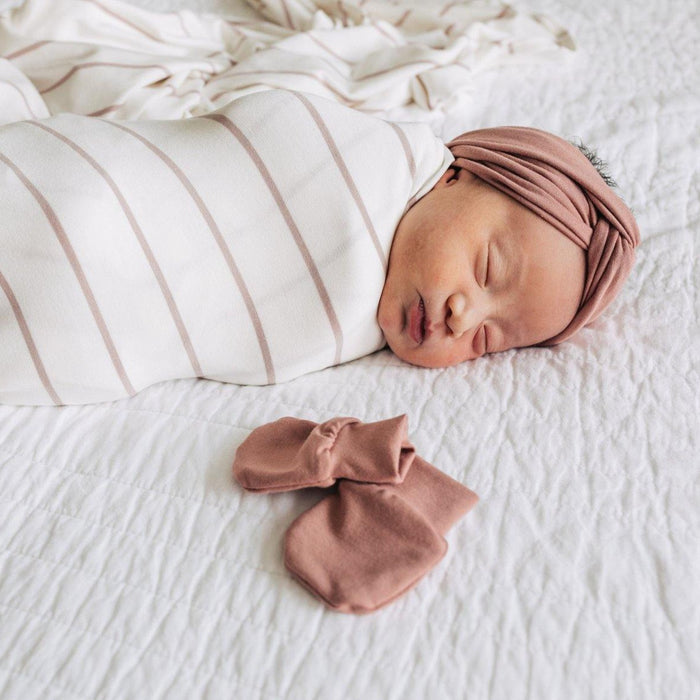 Baby lies next to Lou Lou and Company No Scratch Mittens