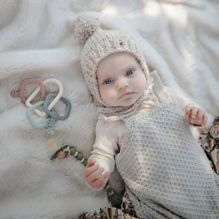 Baby lying next to Mushie Key Toy - Original
