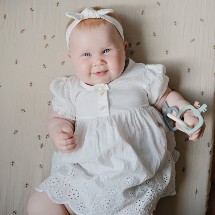 Baby smiles while holding Mushie Key Toy - Original