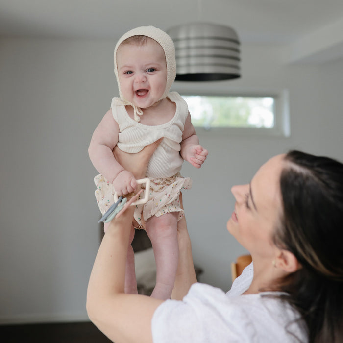Woman holds up baby holding Mushie Key Toy - Original