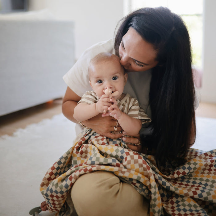 Mom holds baby playing with Mushie Unicorn Figurine Teether - Blush