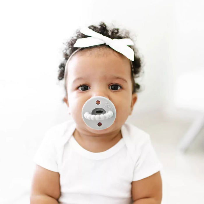 Toddler girl sucks on Ryan and Rose Flat Cutie PAT Pacifier 2 Pack - Grey / White