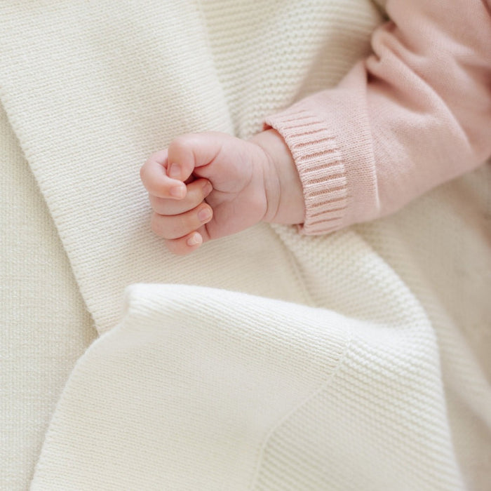 Baby lying on Saranoni Heirloom Cotton Knit Receiving Blanket - Cream