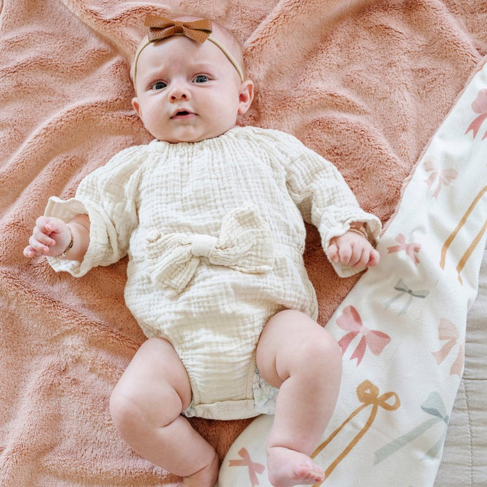 Baby lies on top of Saranoni Receiving Minky / Lush Blanket - Bows