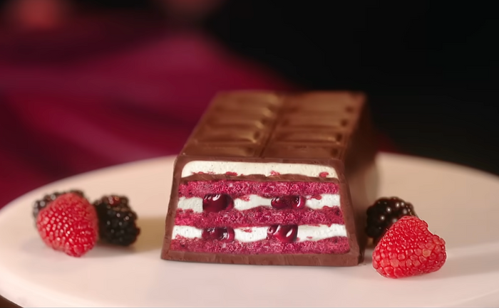 Chocolate cake with raspberry filling on a white plate with berries. Ulker Milk Chocolate Cake with Velvety Red Velvet Base and Forest Berry Sauce – 13.9 oz (395 G)