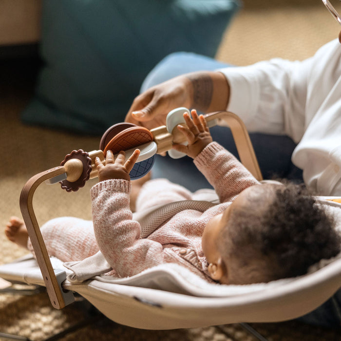 Baby sitting in MIRA bouncer playing with UPPAbaby Wonder Wheel Toy Bar - MIRA accessory attached
